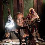 Senyum hangat warga lokal berbagi hasil panen kelapa di perkebunan hijau Indonesia.